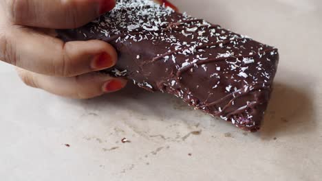 close up of a person holding a chocolate bar with coconut flakes