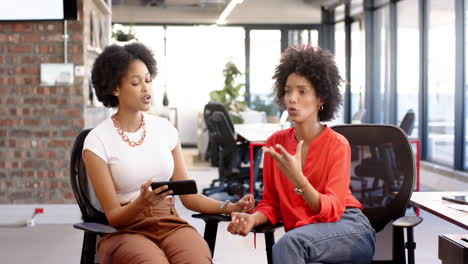 two businesswomen, chatting with tablet in office