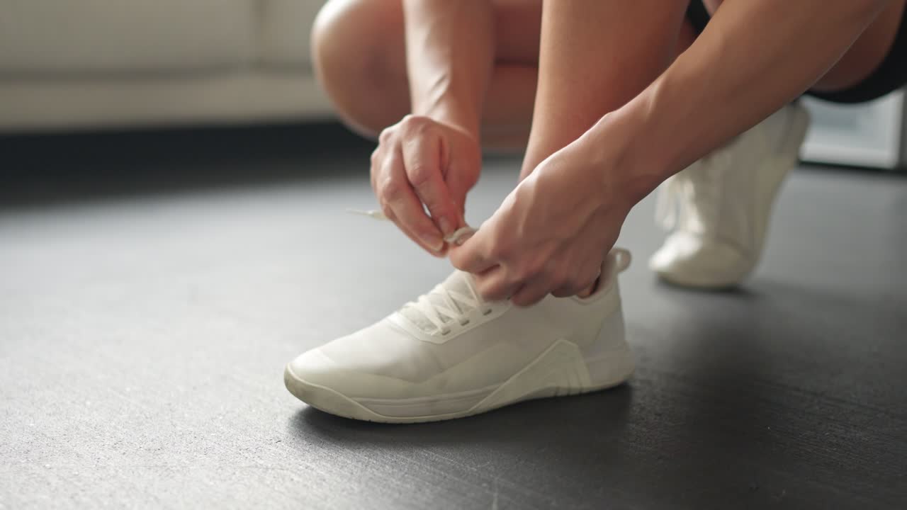 Primo piano di una persona che allaccia le scarpe da ginnastica bianche
