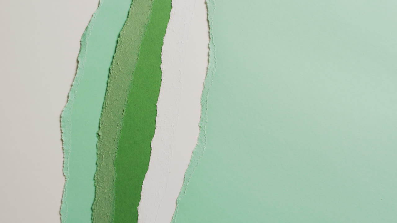 Video in primo piano di pezzi strappati di carta verde e bianca come sfondo.