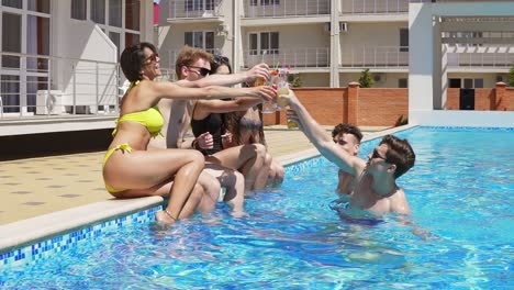 grupo feliz de jóvenes amigos pasando el rato con cócteles y charlando al lado de la piscina en el verano. saludos. piscina