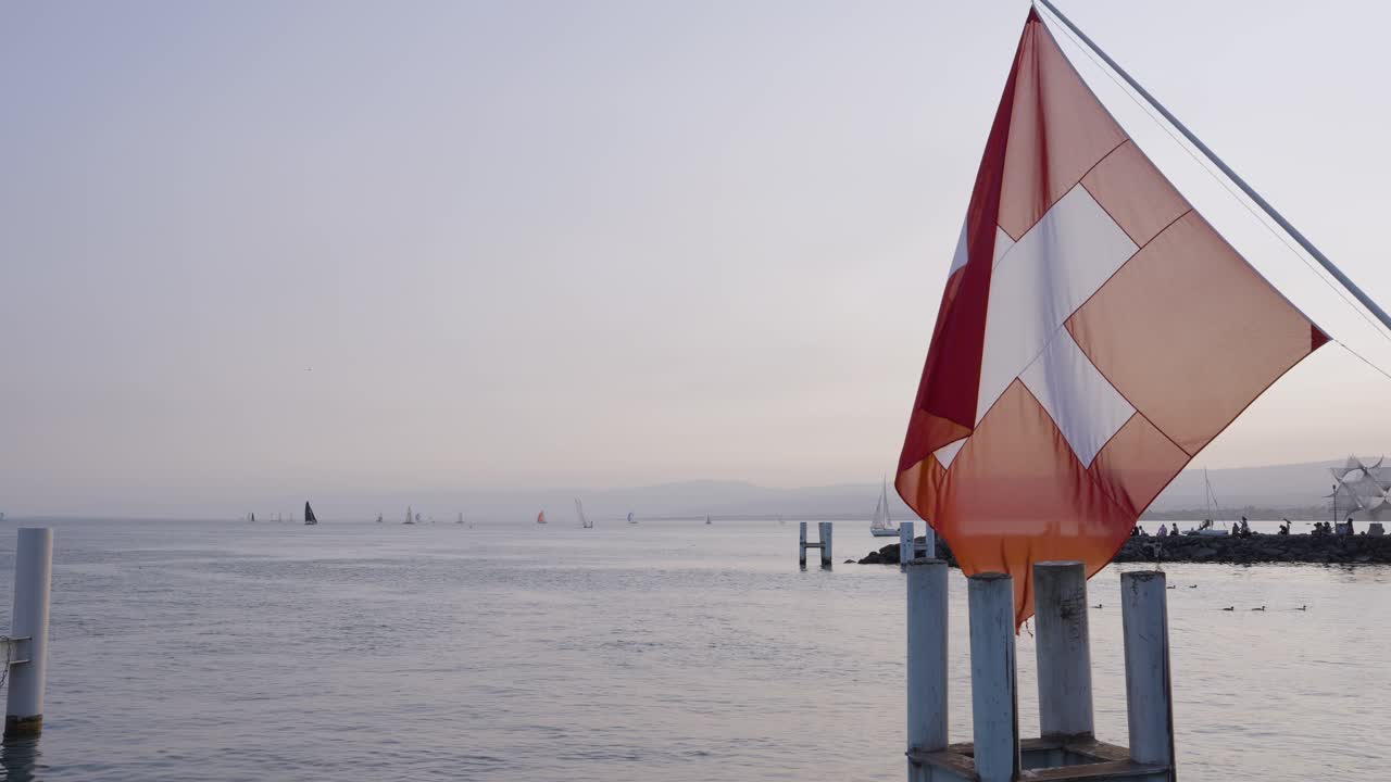 la bandera suiza ondeando lentamente en la brisa al atardecer en el lago ginebra en lausana, suiza