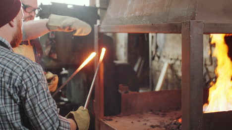 blacksmiths taking off iron from fire in forge