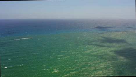 Luftdrohnenaufnahme,-Die-Langsam-über-Den-Atlantik-In-Der-Nähe-Des-Strandes-Von-Singer-Island-Fliegt-Und-An-Einem-Einsamen-Boot-Vorbeischaut,-Während-Wolken-Mit-Schatten-Auf-Dem-Wasser-Spielen