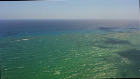 drone aéreo disparado volando lentamente sobre el océano atlántico cerca de la playa de la isla del cantante mirando más allá de un barco solitario mientras las nubes juegan con sombras en el agua
