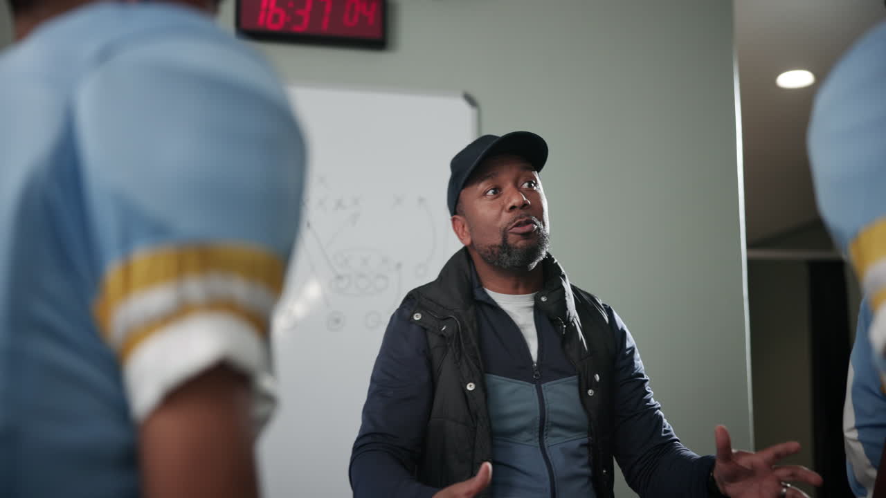 Football coach giving a motivational speech to his team in the locker room