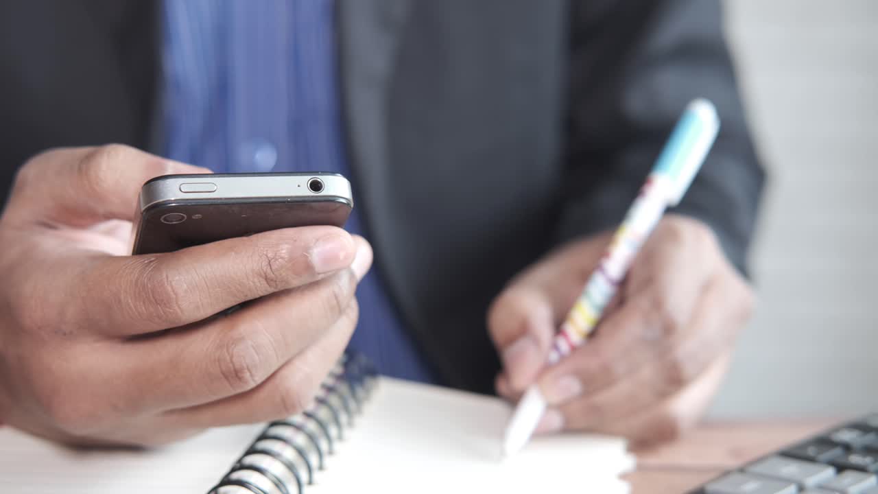 스마트폰을 사용하고 메모를 하는 사업가