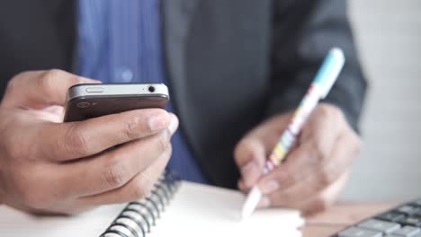 hombre de negocios usando un teléfono inteligente y tomando notas