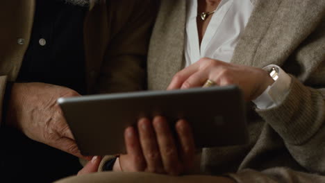 closeup tablet computer in senior couple hands indoors. elderly people pad