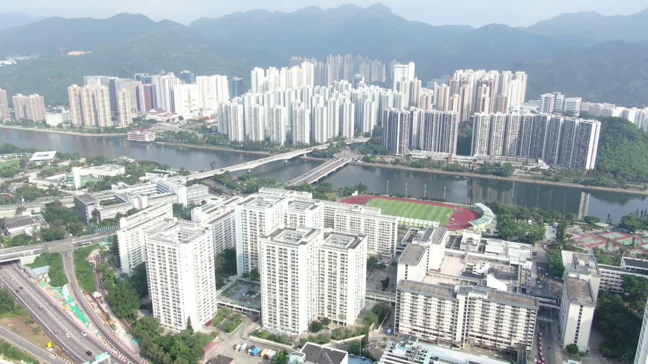 Vista aérea de mega edifícios residenciais em Sha Tin, Hong Kong, com as montanhas Lion Rock ao fundo.