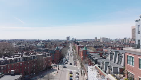 Forwards-fly-above-street-in-large-city.-Red-brick-facades-on-townhouses-along-road-in-urban-neighbourhood.-Boston,-USA