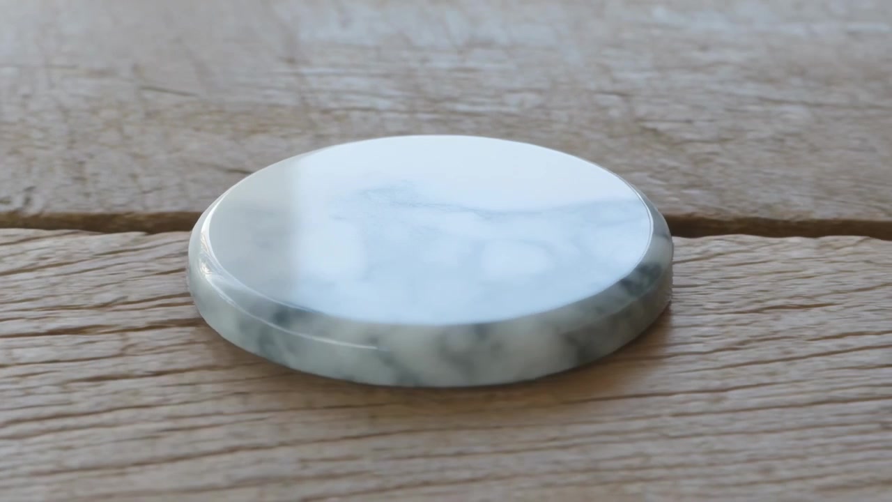 En hvit marmorert disk roterer på en slitt treplanke etter et forsiktig støt, og avslører åringene.