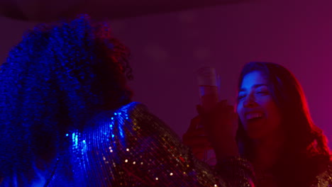 close up of two women in nightclub or bar celebrating doing cheers and drinking alcohol 3