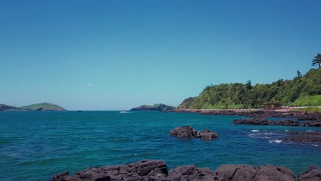 Bajo-Vuelo-Sobre-Rocas-Y-Océano-Azul