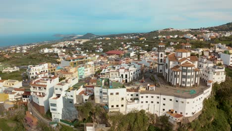 drone vuela lejos de un pueblo con una iglesia a través de un cañón en gran canaria