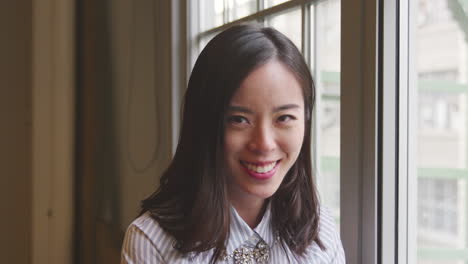 Casually-dressed-Asian-businesswoman-smiling-to-camera