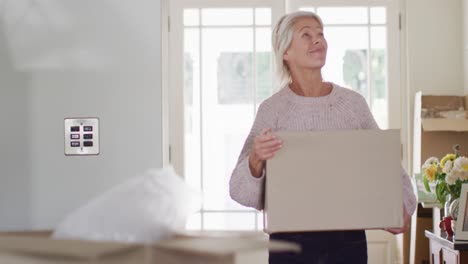 Feliz-Mujer-Caucásica-Mayor-Mudándose-De-Casa,-Desempacando-Cajas-En-La-Cocina