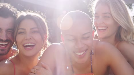 portrait of group of friends outdoors relaxing in swimming pool and enjoying summer pool party