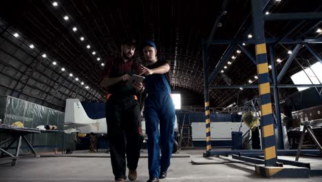 two flight engineers walking through a hangar