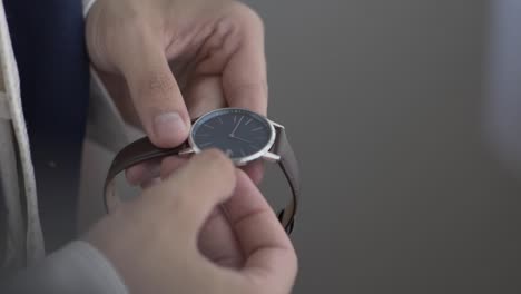 close up man in suit holds a watch