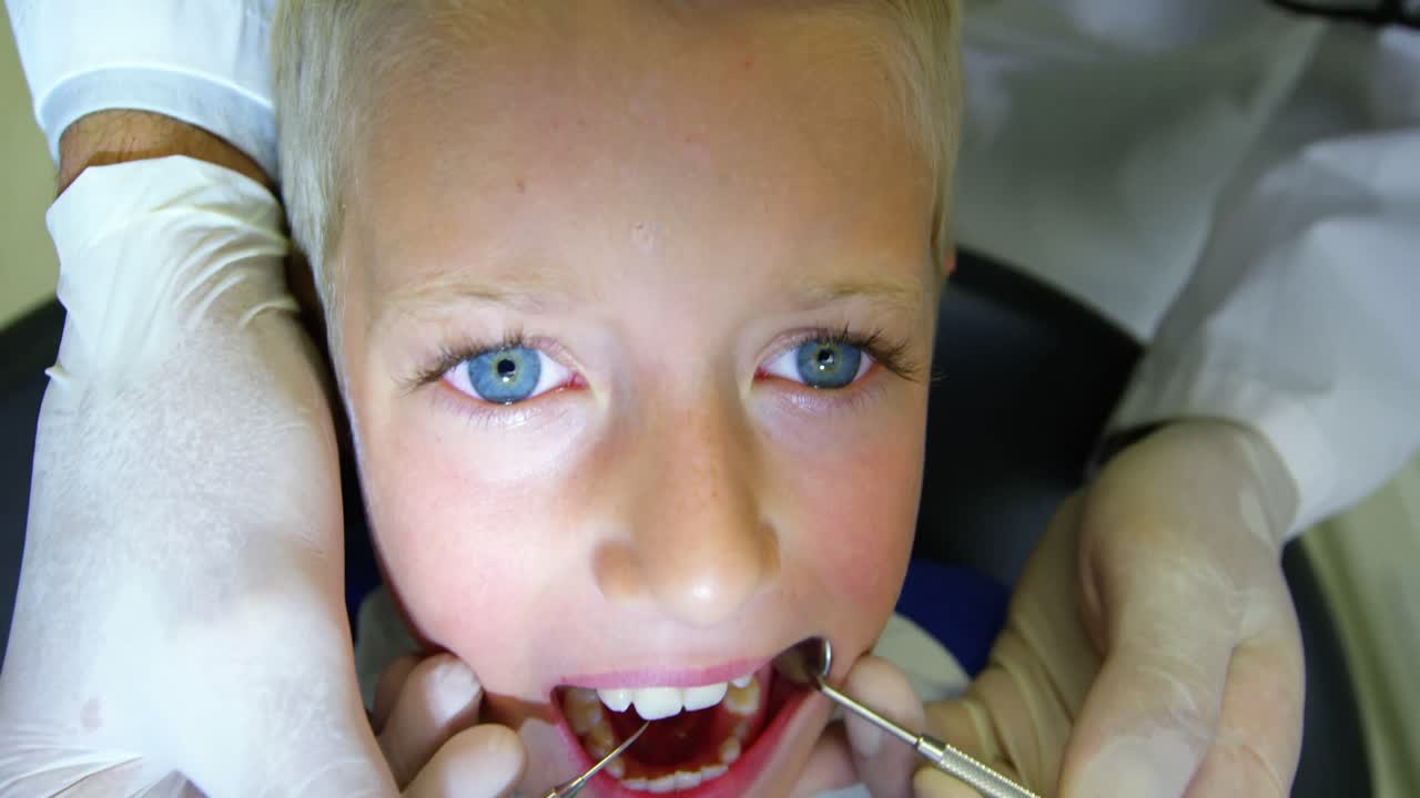 Dentist examining a young patient with tools