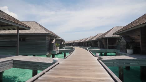 maldivian wooden ocean villas on hot summer day, luxurious sea apartments on crystal clear waters of indian ocean and blue sky with clouds