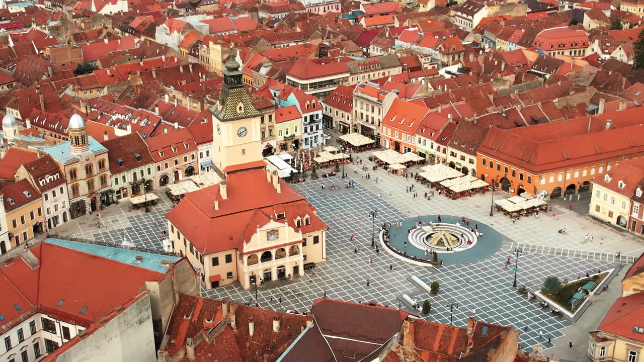 Aerial drone view of main central square in Brasov at night, Romania. Old city centre with County Museum of History, Black church, buildings, nightlights, people