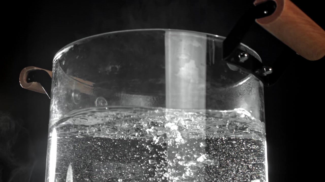 Primo piano di acqua bollente in una pentola di vetro trasparente