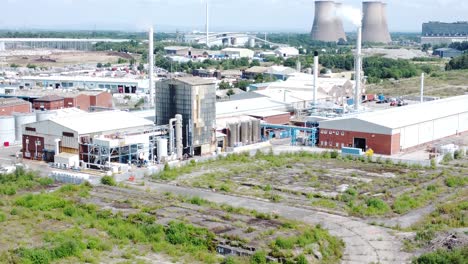 Industrial-warehouse-power-plant-refinery-buildings-under-smokestack-wasteland-aerial-view-rising-forward