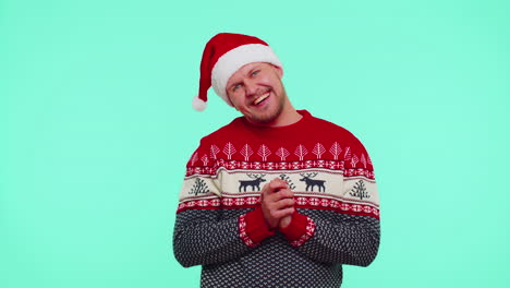 Smiling-man-in-Christmas-sweater-makes-heart-gesture-demonstrates-love-sign-expresses-good-feelings