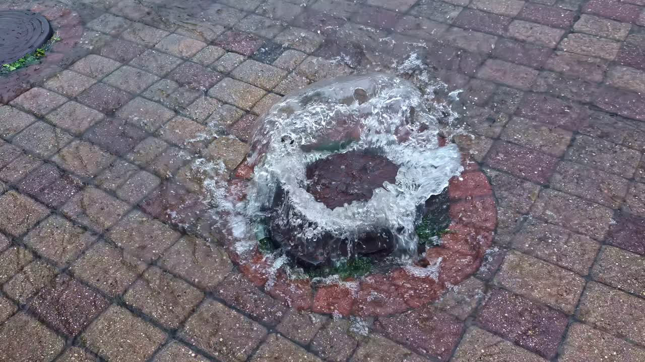 Slow motion view of water overflowing from a drain on road