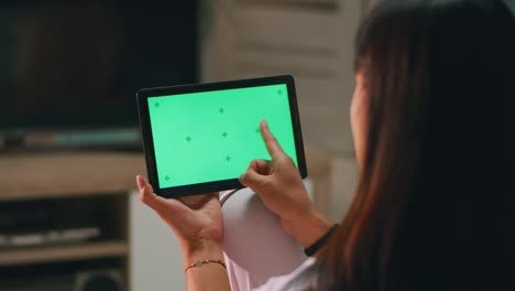 mujer anónima deslizando imágenes en la tableta