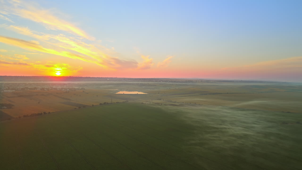 Aerial drone view of village in Moldova at sunset. Few columns of smoke from fires, wide fields, fog in the air