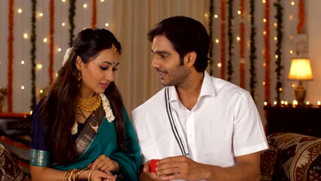 south indian husband with a diwali present for his beautiful wife - happy moment