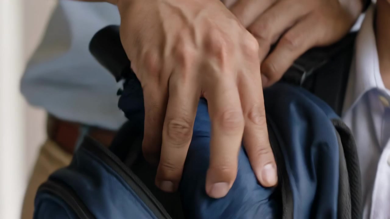 Vedendo lo zaino del figlio, il papà in camicia blu controlla l'ombrello e lo mette nella borsa sul portico per la scuola.