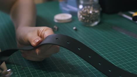 tailor makes holes in leather belt with silver punch pliers