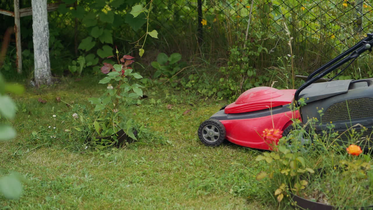 Mowing grass in the garden. Barefoot young girl mowing grass with a lawn mower in garden.