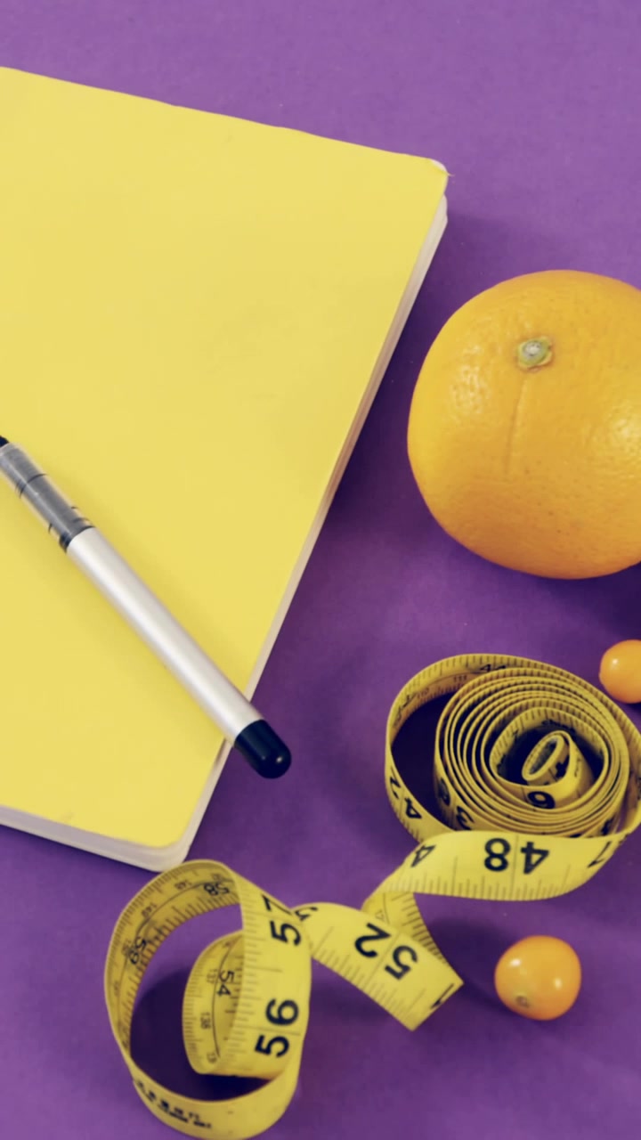 Cellulare, frutta, blocco note, penna e metro a nastro