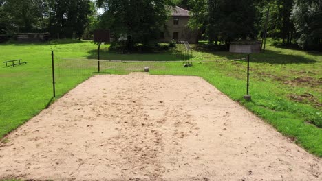 vista aérea de paso lento a través de la cancha de voleibol de arena vacía en el jardín de hierba del campo letón