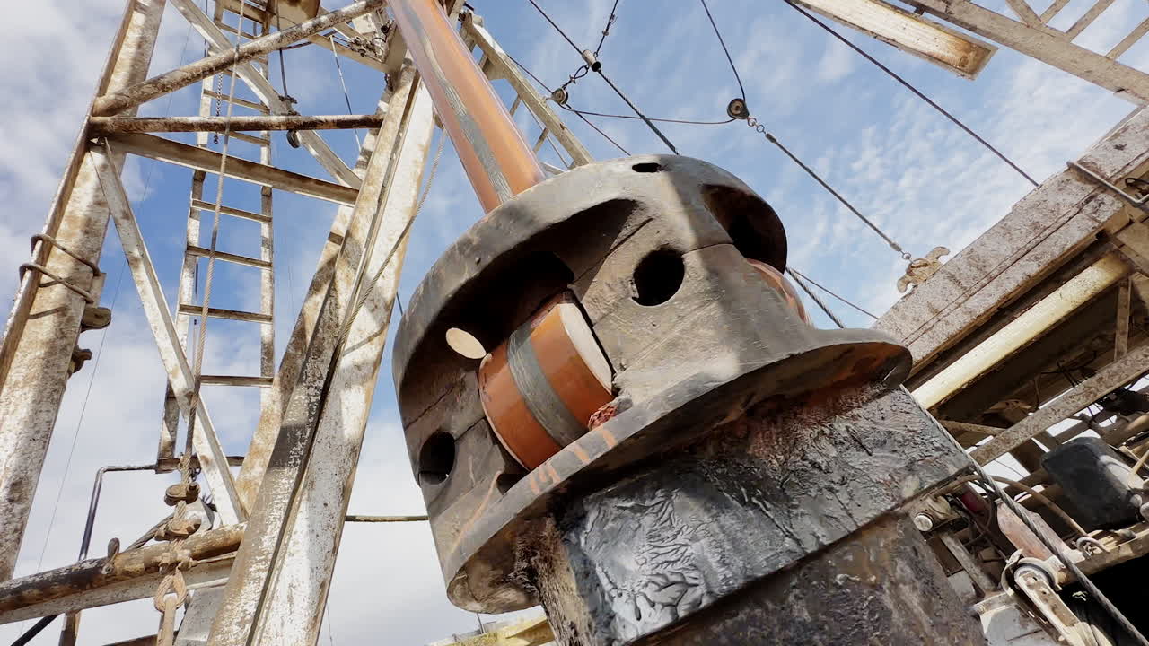 Rotating pole with a boer for oil production. Low angle view at the derrick with drilling equipment.