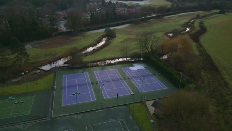 People-playing-in-a-blue-tennis-court-in-the-evening