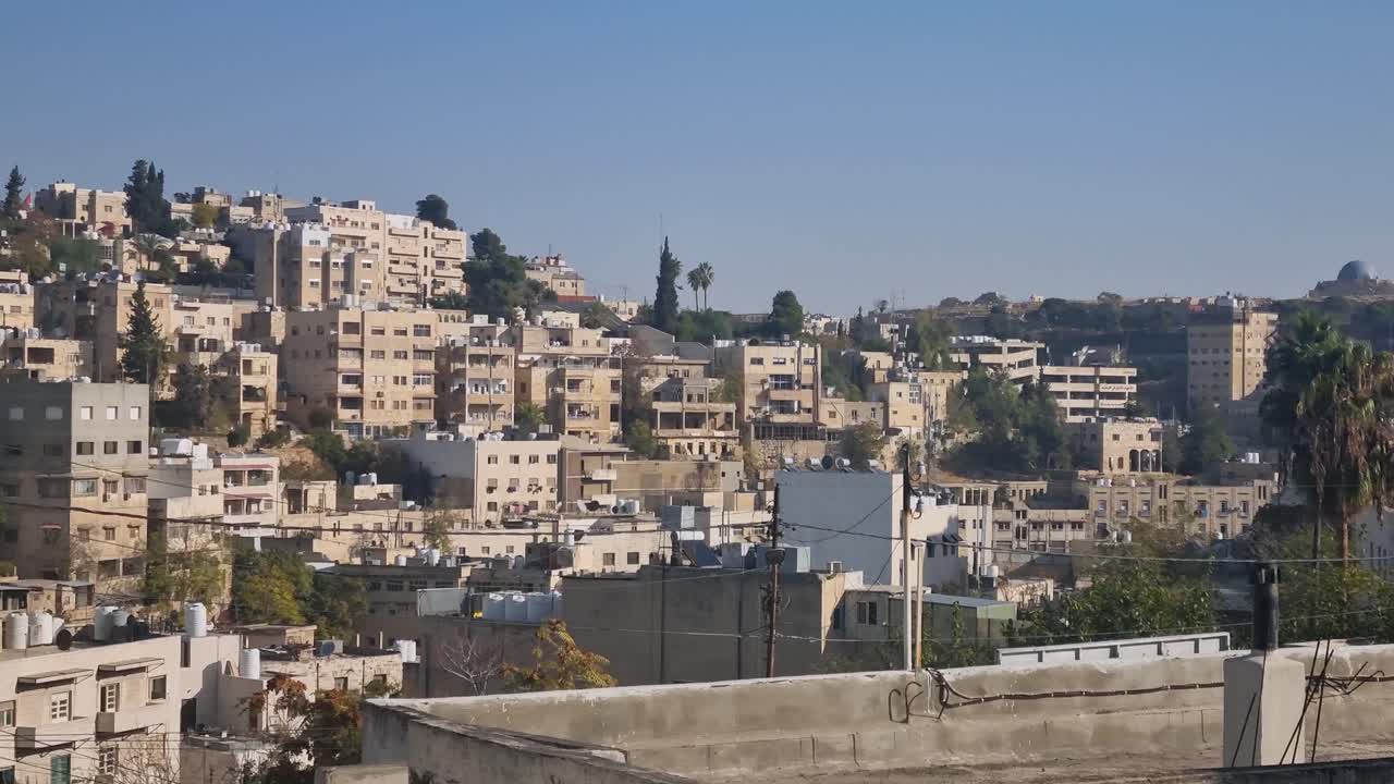 Vista panoramica su un quartiere di Amman, in Giordania, in una luminosa mattina d'inverno, che mostra edifici residenziali in pietra e la vita quotidiana nella vivace capitale mediorientale