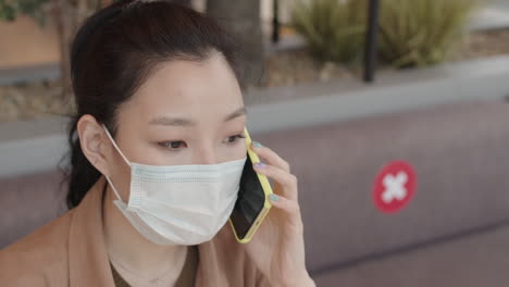 asian woman in mask talking on cellphone