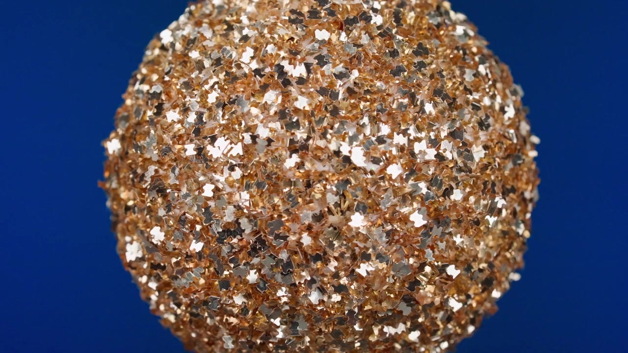 Palla glitterata dorata scintillante su uno sfondo blu
