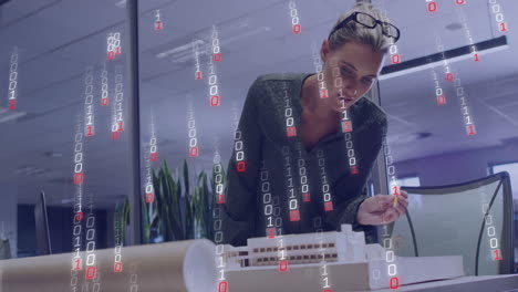 Examining architectural model, woman with binary code animation overlay in office