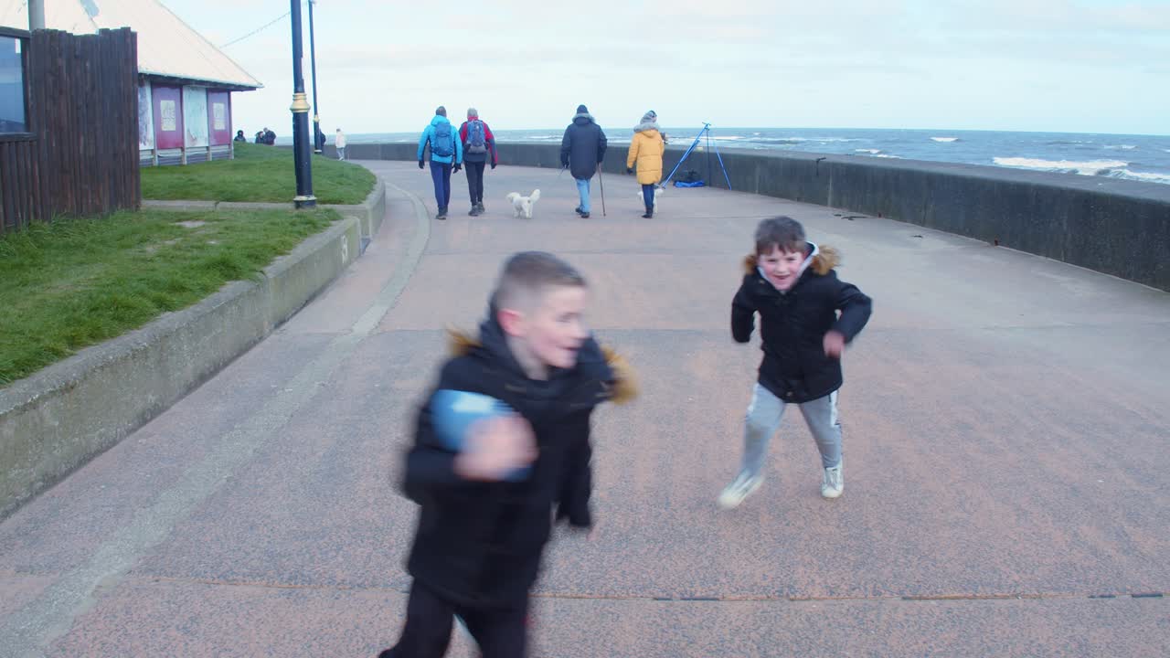 grandmother and grandchildren having fun while playing ball game outdoors during a cold winters day.