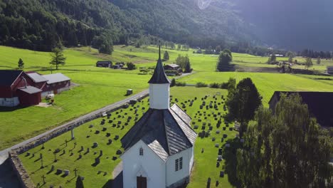 Loen-Kirche-Bei-Sonnenaufgang-–-Morgendliche-Rückwärtsantenne-Vom-Kirchturm-Und-Zurück-–-Enthüllt-Ländliches-Ackerland-Und-Den-örtlichen-Friedhof