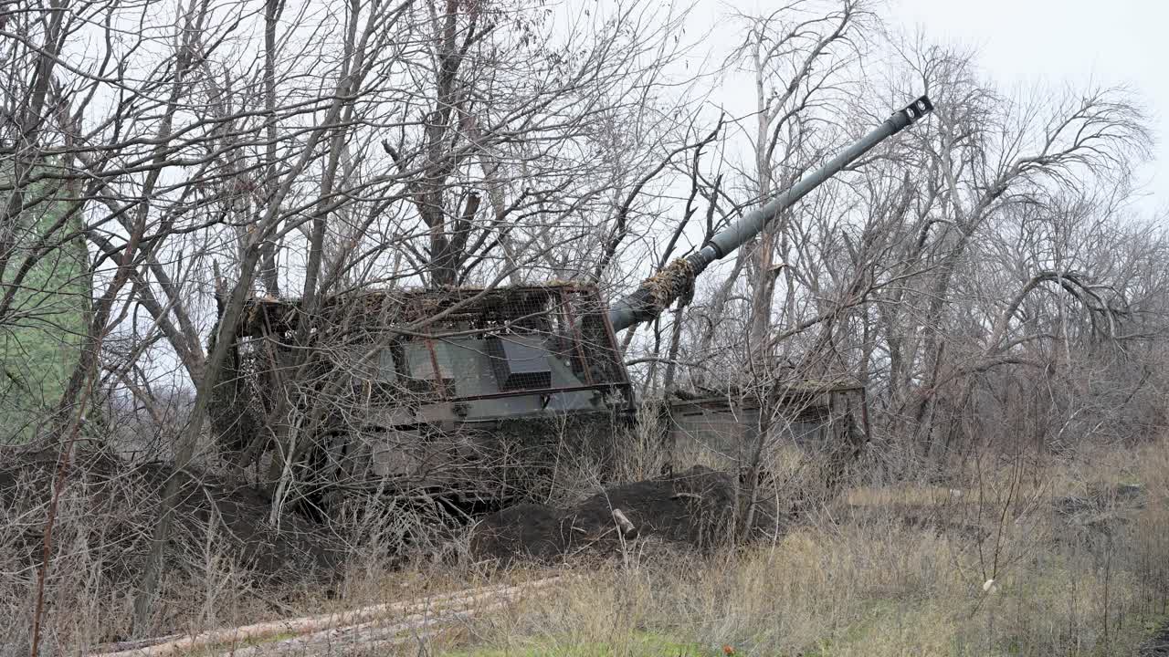 Un obice PzH 2000 di fabbricazione tedesca rompe il camuffamento in Ucraina, preparandosi a spostarsi in posizione di tiro. Questo mostra le moderne tattiche di artiglieria "nascondi e spara".