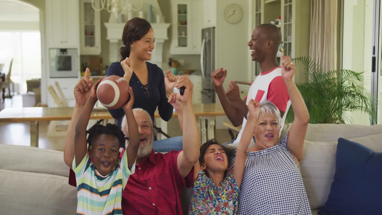 familia de tres generaciones animando mientras ven la televisión en casa