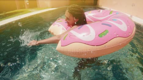 mujer con gafas de sol en bikini azul acostado en rosado inflable donut flotan en la piscina en un día soleado de verano. mira a la cámara. mujer bikini piscina en anillo de goma de sandía vacaciones relajantes